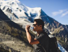 Man drinking water while hiking snow covered mountains