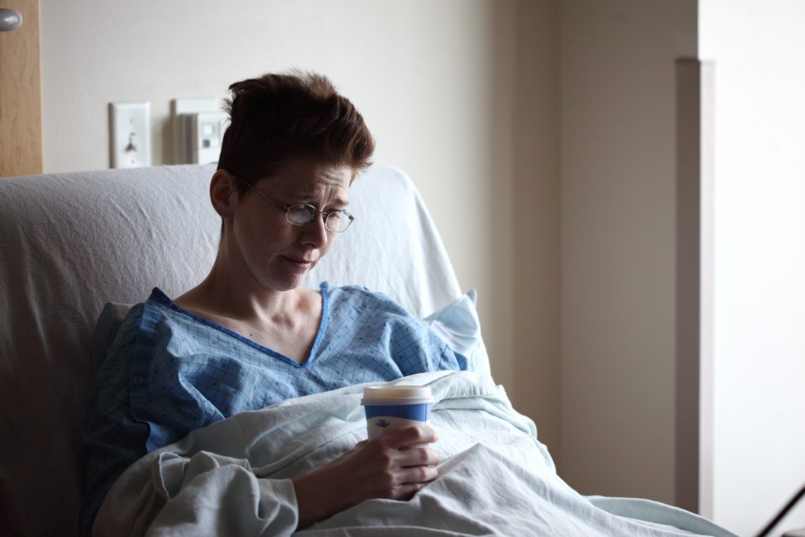 woman on hospital bed holding a coffee cup